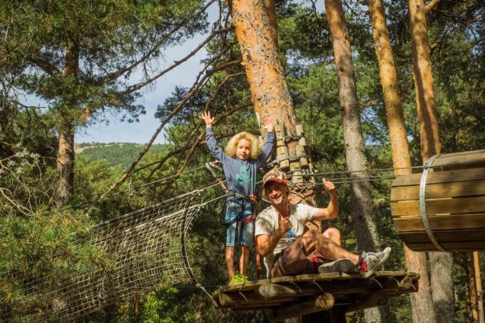 Father and child embrace adventure on a forest zipline in Cercedilla, Spain.